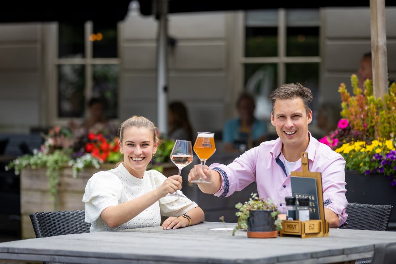 Wout Huijben en partner proosten op het terras van Bij Wout